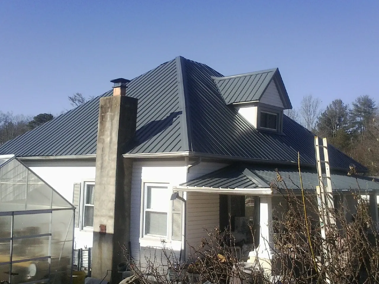 Dark blue standing seam metal roof on a white farmhouse with dormer — Slate & Tile Roof Repair by Roofing Brothers in Studio City