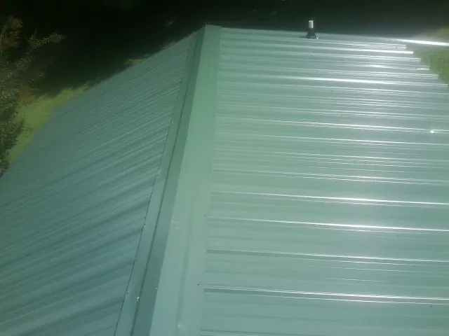 New green metal panels meeting at the ridge of a roof — Flat Roof Repair work by our crew in Studio City