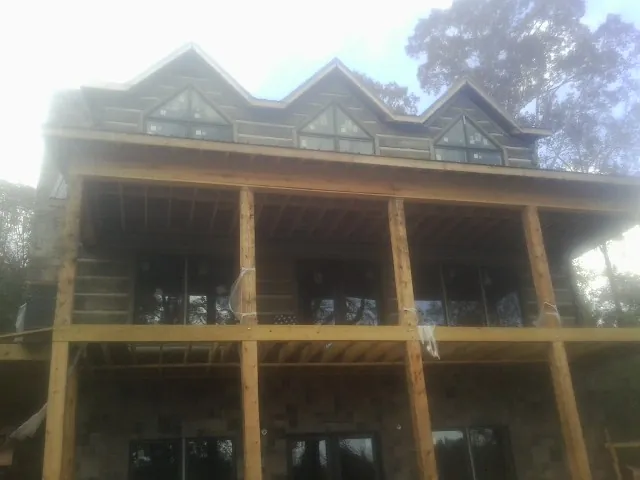 Dormers and porch framing on a large log home under construction — Roof Coating work by our crew in Studio City